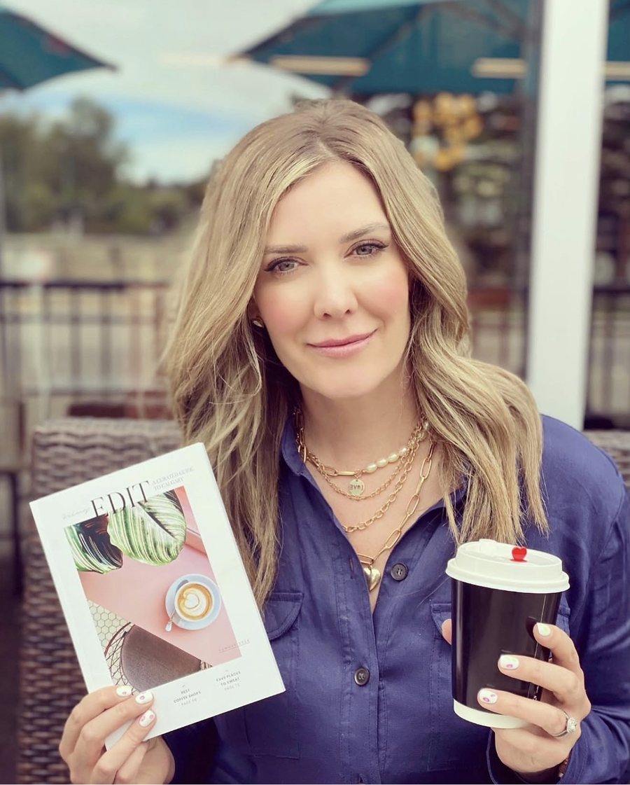 Erin on a patio holding Volume I and II with a coffee